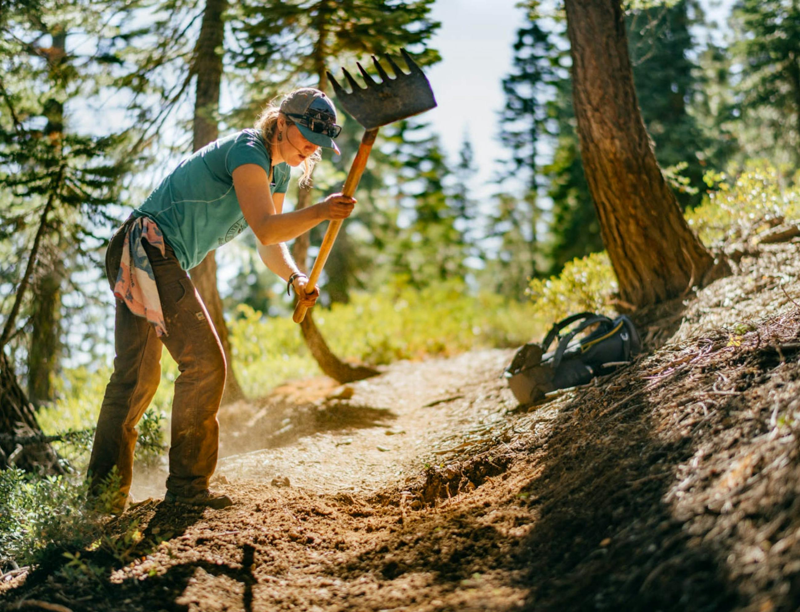 A woman working on a section of trail on a sunny day